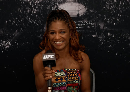 Angela Hill sits in front of a black UFC backdrop