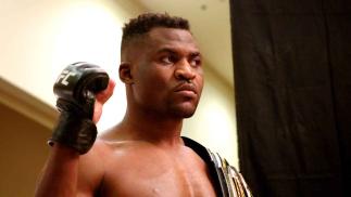 Francis Ngannou posando com o punho erguido e o cinturão do UFC sobre o ombro