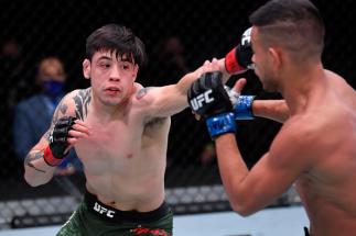 Brandon Moreno of Mexico punches Brandon Royval in their flyweight bout during the UFC 255