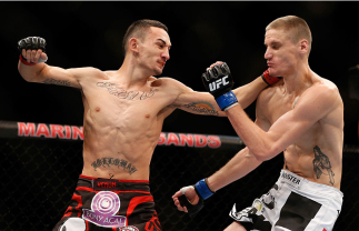 SINGAPORE - JANUARY 04:  (L-R) Max Holloway punches Will Chope in their featherweight bout during the UFC Fight Night event at the Marina Bay Sands Resort on January 4, 2014 in Singapore. (Photo by Josh Hedges/Zuffa LLC/Zuffa LLC via Getty Images)