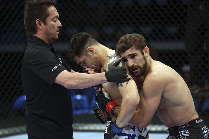 CALGARY, CANADA - JULY 21: (L-R) Referee Mario Yamasaki holds Daniel Pineda up as Antonio Carvalho hugs him after knocking Pineda out in the first round during their featherweight bout at UFC 149 inside the Scotiabank Saddledome on July 21, 2012 in Calga