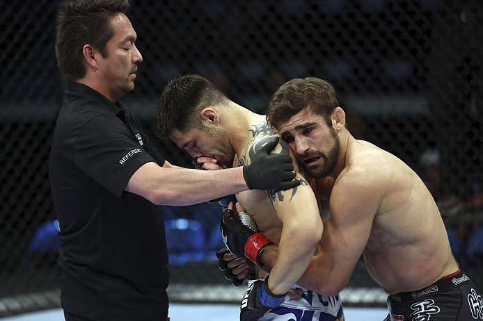 CALGARY, CANADA - JULY 21:  (L-R) Referee Mario Yamasaki holds Daniel Pineda up as Antonio Carvalho hugs him after knocking Pineda out in the first round during their featherweight bout at UFC 149 inside the Scotiabank Saddledome on July 21, 2012 in Calga