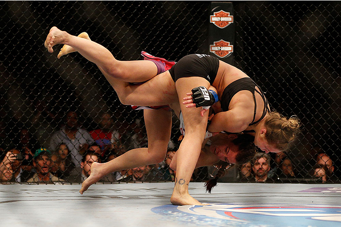 LAS VEGAS, NV - DECEMBER 28:  Ronda Rousey (black shorts) throws Miesha Tate in their UFC women's bantamweight championship bout during the UFC 168 event at the MGM Grand Garden Arena on December 28, 2013 in Las Vegas, Nevada. (Photo by Josh Hedges/Zuffa 