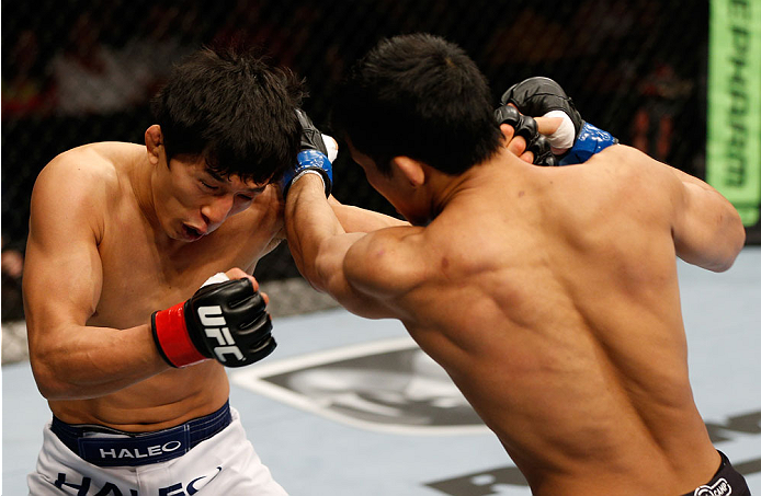 BRISBANE, AUSTRALIA - DECEMBER 07: (R-L) Nam Phan and Takeya Mizugaki trade punches in their bantamweight fight during the UFC Fight Night event at the Brisbane Entertainment Centre on December 7, 2013 in Brisbane, Australia. (Photo by Josh Hedges/Zuffa