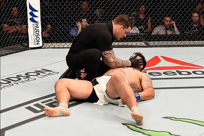 BRISBANE, AUSTRALIA - MARCH 20:  Referee Marc Goddard tends to Frank Mir of the United States as he lies on the Octagon mat after being defeated by Mark Hunt of New Zealand by KO in their heavyweight bout during the UFC Fight Night event at the Brisbane E