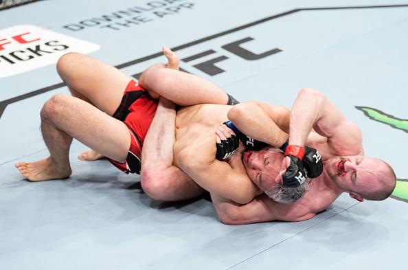 Gunnar Nelson nas costas de Takashi Sato com um triângulo na linha de cintura e golpeando a cabeça com socos no UFC Londres (Chris Unger/Zuffa LLC)