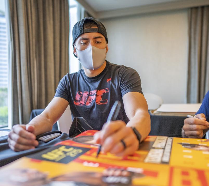 Steve Garcia signs UFC 275 posters during fight week in Singapore, June 2022 (Photo by Juan Cardenas/Zuffa LLC)