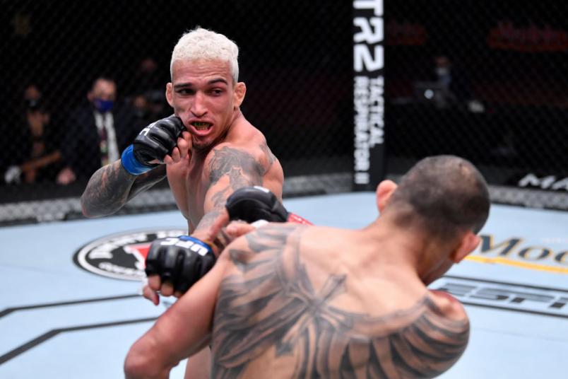 LAS VEGAS, NEVADA - DECEMBER 12: (L-R) Charles Oliveira of Brazil punches Tony Ferguson in their lightweight bout during the UFC 256